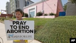 FILE - An abortion-rights opponent sings to herself outside the Jackson Women's Health Organization clinic in Jackson, Miss., Oct. 2, 2019.