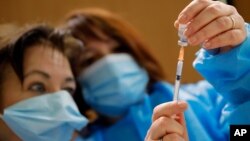 Les infirmières, Ines, à gauche, et Valérie préparent un vaccin Pfizer-BioNTech COVID-19 à administrer à un agent de santé dans un centre de vaccination contre les coronavirus à Poissy, en France, le vendredi 8 janvier 2021.
