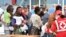 FILE - Migrants line up at a Red Cross tent after they disembarked from the Irish Navy vessel LE Niamh at the Messina harbor in Sicily, Italy, Aug. 24, 2015.