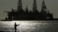 FILE - A man wears a face mark as he fishes near docked oil drilling platforms, on May 8, 2020, in Port Aransas, Texas. 