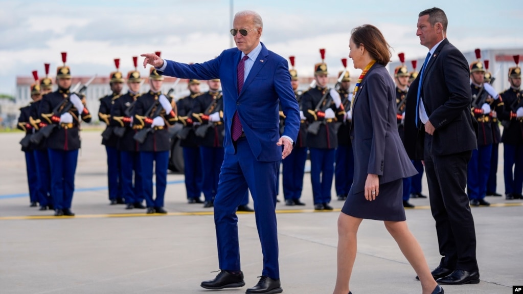 El presidente Joe Biden habla con la embajadora de Estados Unidos en Francia, Denise Campbell Bauer, segunda desde la derecha, junto a una guardia de honor francesa después de llegar al aeropuerto de Orly, al sur de París, el miércoles 5 de junio de 2024.