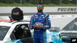 FILE - Bubba Wallace stands by his car before the start of the NASCAR Cup Series auto race at Pocono Raceway, in Long Pond, Pennsylvania, June 28, 2020.