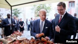 Wakil Presiden AS Joe Biden (kiri) dan Perdana Menteri Serbia Aleksandar Vucic melihat-lihat cenderamata tradisional saat jalan-jalan di kota Belgrad, Serbia (16/8). (Reuters/Djordje Kojadinovic)