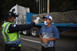 A transit police officer checks the temperature of a truck driver as a preventive measure against the new coronavirus, during a partial curfew ordered by the government in Villa Nueva, Guatemala, on April 2, 2020.