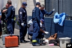 Phoenix, Arizona, firefighters give medical aid to a homeless man on May 30, 2024. Sizzling sidewalks and unshaded playgrounds increasingly are posing risks for surface burns as temperatures reach new highs during summer in Southwest U.S. cities such as Phoenix and Las Vegas.