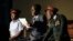 In this photo taken March, 28, 2018, actor Khetani Banda, playing former Zimbabwean president Robert Mugabe, center, reads a speech flanked by army generals during a play dramatizing the events leading to his resignation, in Harare, Zimbabwe.