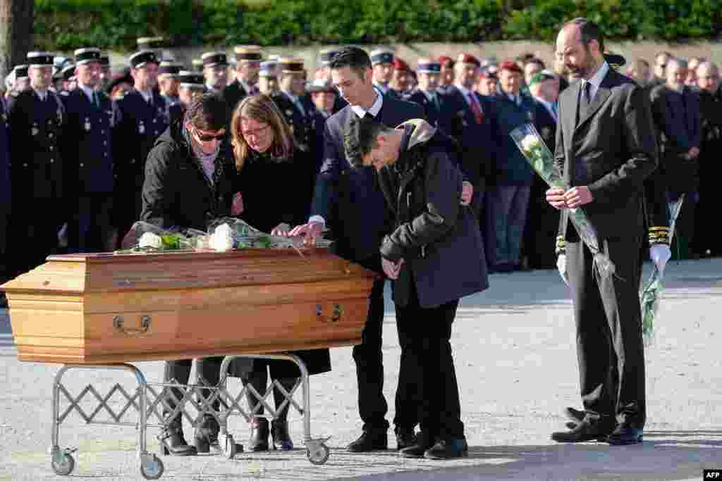 French Prime Minister Edouard Philippe (R) holds a white rose to lay the coffin as he watches family members pay their last respects during the funeral service for the three people killed in a terrorist attack in the town of Trebes.