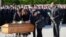 FILE - French Prime Minister Edouard Philippe holds a white rose to lay on the coffin as he watches family members pay their last respects during the funeral service for the three of the people killed in a terrorist attack in the town of Trebes, March 29, 2018. 