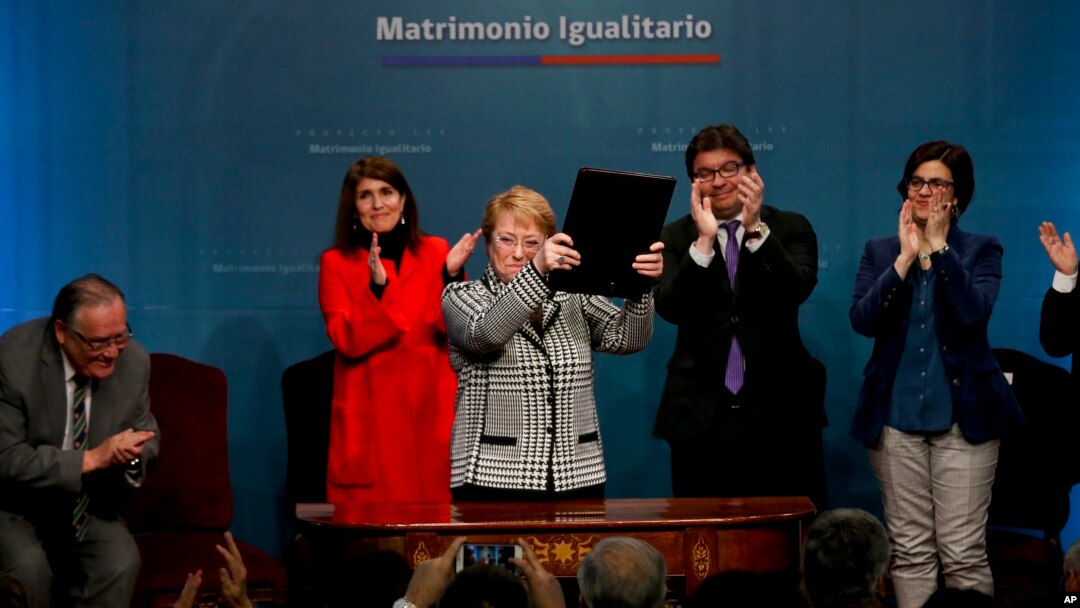 Chile's President Michelle Bachelet holds up a portfolio containing her signed proposal for a same-sex marriage bill at La Moneda presidential palace in Santiago, Chile, Aug. 28, 2017.