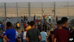 Protesters chant while try to climb the fence of the Gaza Strip's border with Israel, east of Gaza City, Aug. 21, 2021.