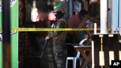 Un soldado vigla el perímetro de un sitio donde se cometió un delito en un pequeño mercado, el 27 de marzo de 2022, en San Salvador, El Salvador.