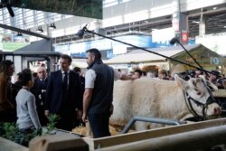 French President Emmanuel Macron speaks with a farmer during a visit to the International Agriculture Fair (Salon de l'Agriculture) at the Porte de Versailles exhibition center in Paris, Feb. 22, 2020.