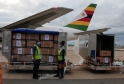 Workers offload boxes as the country's first batch of coronavirus disease (COVID-19) vaccines arrives from China, in Harare, Zimbabwe, February 15,2021. REUTERS/Philimon Bulawayo