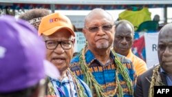 Bougainville regional president John Momis, left, speaks to the media before casting his ballot in an historical independence vote as the Papua New Guinea minister for Bougainville affairs, Puka Temu, center, looks on in Buka on Nov. 23, 2019. 
