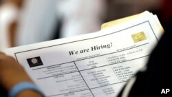 FILE - A job applicant looks at job listings for the Riverside Hotel at a job fair hosted by Job News South Florida, in Sunrise, Fla.