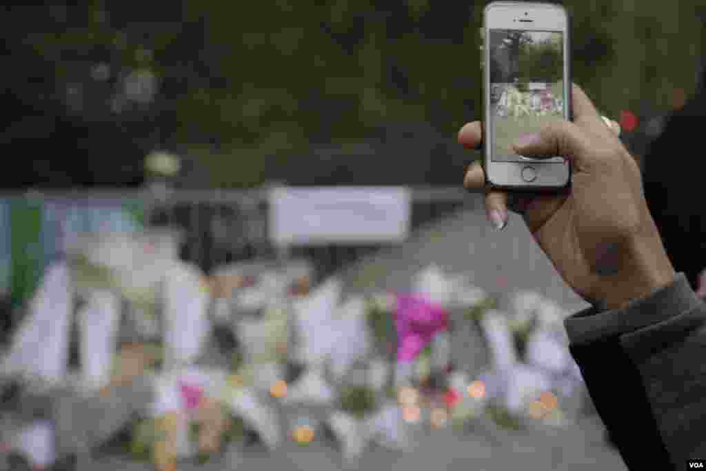 A mourner takes a photo of a memorial outside the Bataclan Concert Hall a day after more than 120 people were killed in a series of attacks in Paris, Nov. 14, 2015.