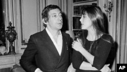 ARCHIVO - El cantautor francés Serge Gainsbourg, a la izquierda, y la actriz Jane Birkin conversan mientras visitan la casa de modas de Pierre Balmain, enero de 1969.