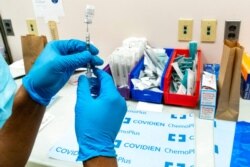 A pharmacist prepares a syringe with the Pfizer-BioNTech COVID-19 vaccine at a COVID-19 vaccination site at NYC Health + Hospitals Metropolitan, in New York, Feb. 18, 2021.