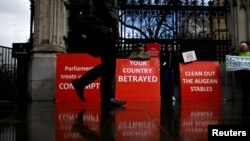 FILE - A person walks past pro-Brexit protesters outside the Houses of Parliament, April 4, 2019. 