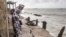 FILE - A woman looks at a crack in the walkway that leads to the mosque in Bargny, Senegal, on September 18, 2020. Fishing villages like Bargny have been fighting the rising seas for decades.