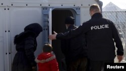 FILE - Migrants are accompanied by Czech police officers at Macedonian Greek border near Gevgelija, Macedonia, Feb. 19, 2016. 