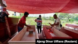 Pembuat peti mati menyiapkan pesanan peti untuk para korban COVID-19 di sebuah bengkel di dalam kompleks pemakaman di Jakarta, 29 Juni 2021. (Foto: REUTERS/Ajeng Dinar Ulfiana)