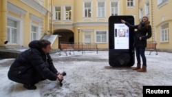 FILE - A woman poses for a photo near the iPhone-shaped monument to Apple co-founder Steve Jobs at the State University of Information Technologies, Mechanics and Optics in St. Petersburg in January 2013.