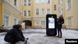 FILE - A woman poses for a photo near the iPhone-shaped monument to Apple co-founder Steve Jobs at the State University of Information Technologies, Mechanics and Optics in St. Petersburg in January 2013.