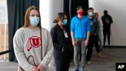 FILE - University of Utah student Abigail Shull waits in line before taking a rapid COVID-19 test at the University of Utah student testing site in Salt Lake City, Nov. 18, 2020.