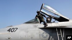 FILE - A U.S. fighter pilot gets into the cockpit of a Super Hornet jet before launching from the deck of the U.S.S. Dwight D. Eisenhower aircraft carrier towards targets in Syria. Nov. 22, 2016.