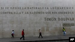 La gente pasa por delante de un mural en piedra con frases de Simón Bolívar cerca de la Asamblea Nacional de Venezuela en Caracas, en enero de 2020.