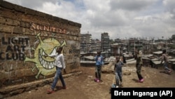 FILE - In this April 22, 2020, file photo, children walk past an informational mural depicting the coronavirus and warning people to sanitize to prevent its spread. (AP Photo/Brian Inganga, File)