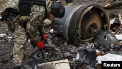 2024年1月2日，在乌克兰哈尔科夫，一名炸弹小组成员在俄罗斯导弹袭击中住宅楼严重受损的地点，在一枚不明导弹的残骸旁工作。