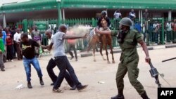 A police officer fires pepper spray at supporters of the opposition United Party for National Development outside the Woodlands Police Station in Lusaka, March 2, 2016. 