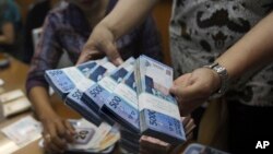 Seorang pegawai tengah menghitung lembaran uang rupiah di sebuah penukaran uang di Jakarta (Foto: dok).