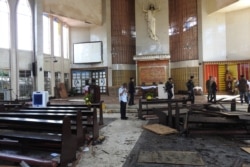 FILE - Philippine soldiers walk past the damaged area of a Catholic cathedral in Jolo town, Sulu province, in southern island of Mindanao, Jan. 28, 2019, a day after two explosions tore through the cathedral.