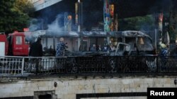 Anggota pertahanan sipil memadamkan api bus di lokasi serangan bom pinggir jalan di pusat Damaskus, Suriah, 20 Oktober 2021. (SANA/Handout via REUTERS)