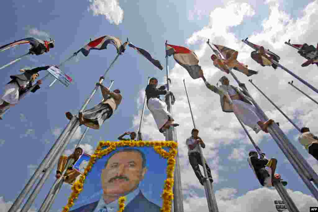 Supporters of Yemen's President Ali Abduallah Saleh stand on flag poles celebrating his return to Sanaa, Yemen, Friday, Sept. 23, 2011. (AP Photo/Hani Mohammed)