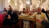 The Latin Patriarch of Jerusalem Fouad Twal (2nd R) carries a statuette of baby Jesus during Christmas midnight mass at the Church of St. Catherine, which is connected to the Church of the Nativity, in the West Bank town of Bethlehem. 