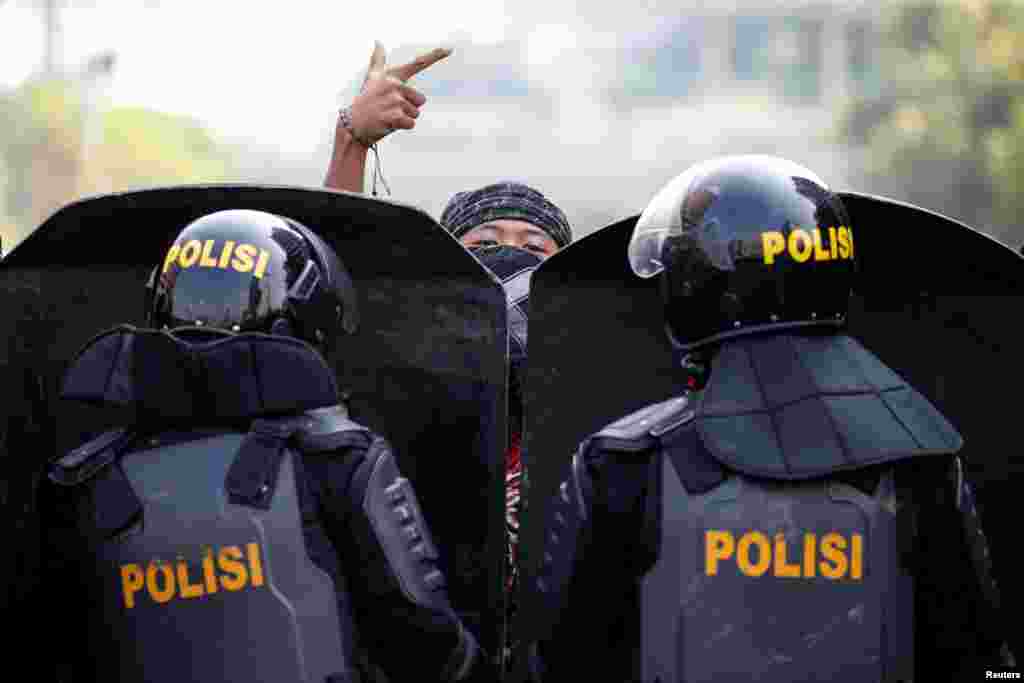 Seorang pendemo memberi isyarat sementara aparat Brimob bersiaga dalam demo di depan kantor pusat Bawaslu di Jakarta, 22 Mei 2019. (Foto: Reuters/Willy Kurniawan)