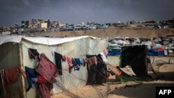 FILE - A displaced Palestinian woman hangs laundry to dry outside a tent at a makeshift camp on the Egyptian border, west of Rafah in the southern Gaza Strip on January 14, 2024.