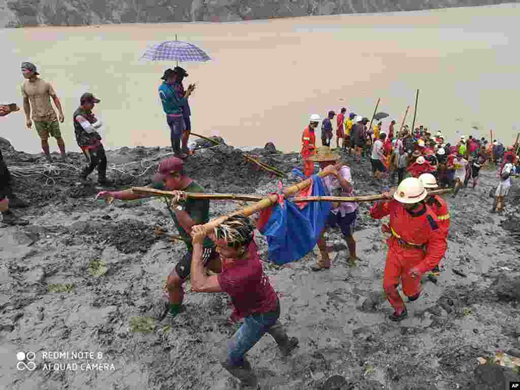 In this photo released from Myanmar Fire Service Department, rescuers carry a recovered body of a victim of a landslide from a jade mining area in Hpakant, Kachin state, northern Myanmar.