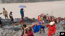 In this photo released from Myanmar Fire Service Department, rescuers carry a recovered body of a victim of a landslide from a jade mining area in Hpakant, Kachin state, northern Myanmar.