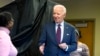 President Joe Biden, right, holding an "I Voted Early" sticker, reaches to shake the hand of a poll worker upon exiting the voting booth after casting his early-voting ballot for the 2024 general elections, in New Castle, Delaware, Oct. 28, 2024. 