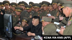 ຜູ້ນຳເກົາຫຼີເໜືອ ທ່ານ Kim Jong Un (ກາງ) ພວມເບິ່ງ ຄອມພິວເຕີ້ ຂະນະທີ່ທ່ານກວດກາເບິ່ງການຍິງປືນໃຫຍ່ ໃສ່ເປົ້າໝາຍ ໃນເຂດນ່ານນ້ຳທາງກ້ຳຕາເວັນຕົກສຽງໃຕ້ ແຫ່ງນຶ່ງ ຂອງເກົາຫຼີເໜືອ.