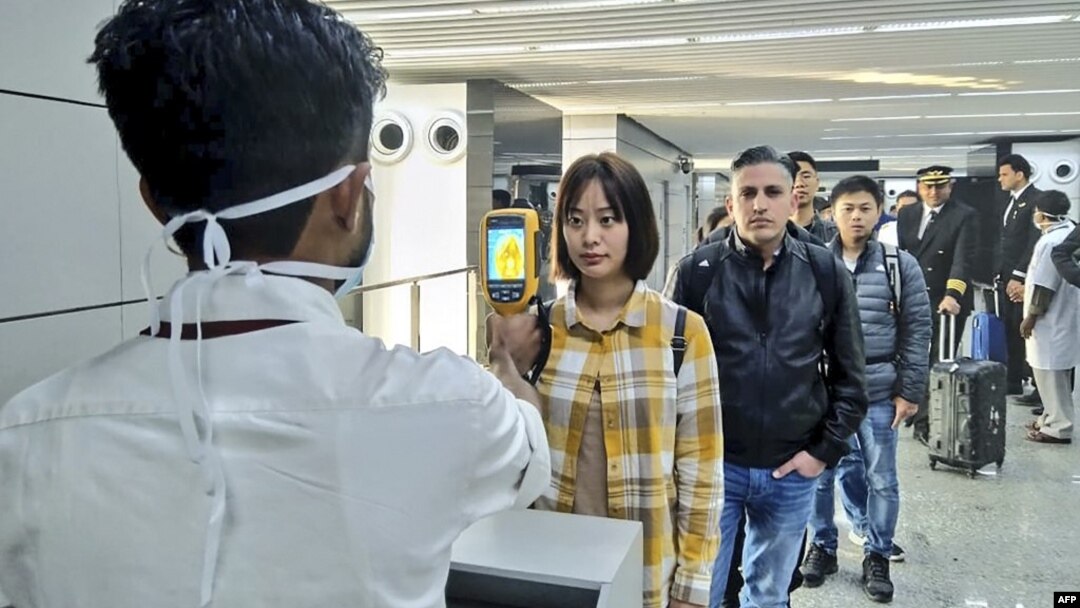Petugas kesehatan memeriksa penumpang yang baru tiba di bandara Chandra Bose, Kolkata, India, Selasa (21/1) untuk mendeteksi kemungkinan terjangkit virus corona. 