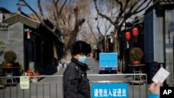 지난 1일 중국 베이징 난루오꾸샹에서 마스크를 쓴 공안이 출입을 통제하자, 주민이 출입증을 보이고 있다.