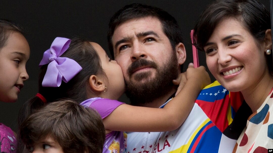 Maria Daniela kisses her father Daniel Ceballos, former mayor of the western city of San Cristobal, as he looks out from an apartment window with his wife Patricia de Ceballos, right, daughter Maria Veronica, left, and son Juan Daniel in Caracas, Venezuel