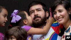 Maria Daniela kisses her father Daniel Ceballos, former mayor of the western city of San Cristobal, as he looks out from an apartment window with his wife Patricia de Ceballos, right, daughter Maria Veronica, left, and son Juan Daniel in Caracas, Venezuel