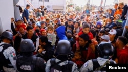 Migrants, mostly from Venezuela, try to cross the barrier of the Mexican army, to enter the Paso del Norte international bridge, during a protest to request asylum in the United States, seen from Ciudad Juarez, Mexico, March 12, 2023.